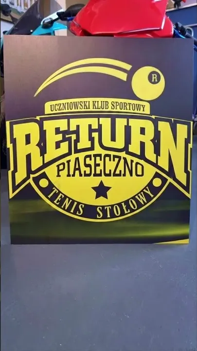 Logo Uczniowskiego Klubu Sportowego Return Piaseczno (tenis stołowy) wydrukowane bezpośrednio na ścianie klubu.