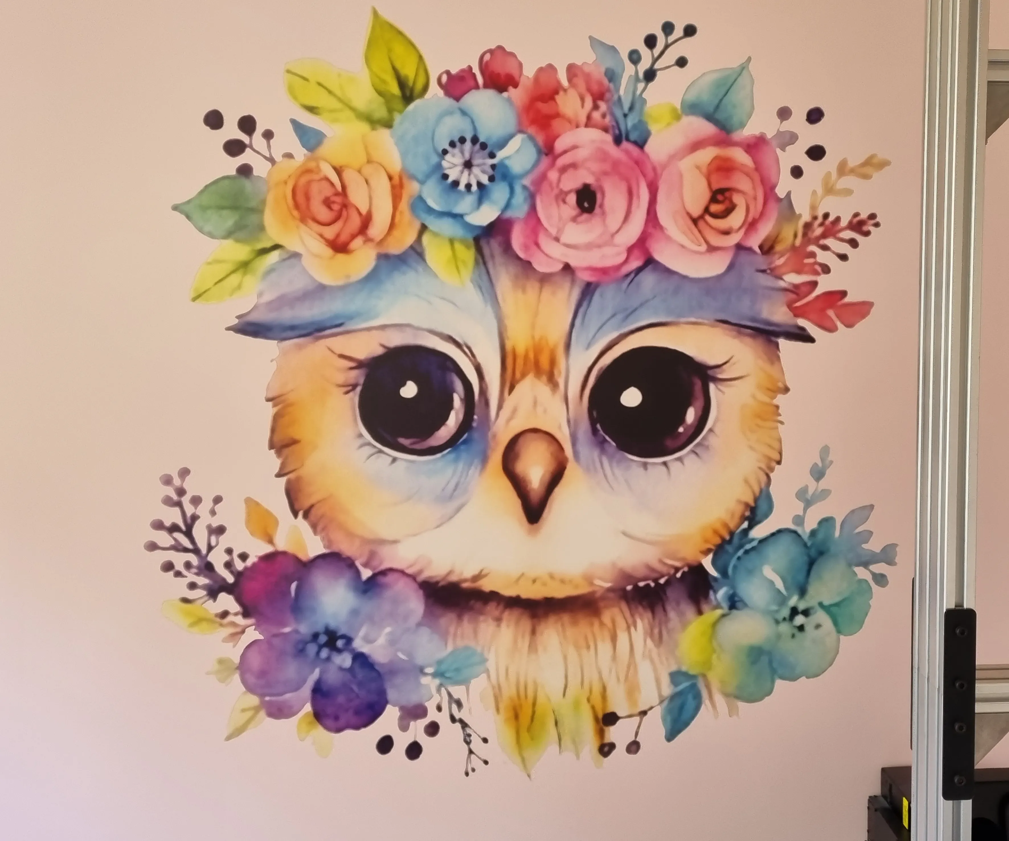 Kolorowa sowa w wieńcu kwiatów, zbliżenie na jasnej ścianie.